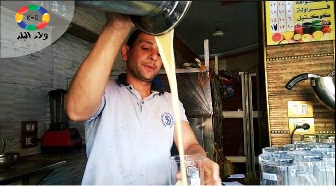 احد العمال بمحل عصير وهو يصب عصير القصب - منال محمود