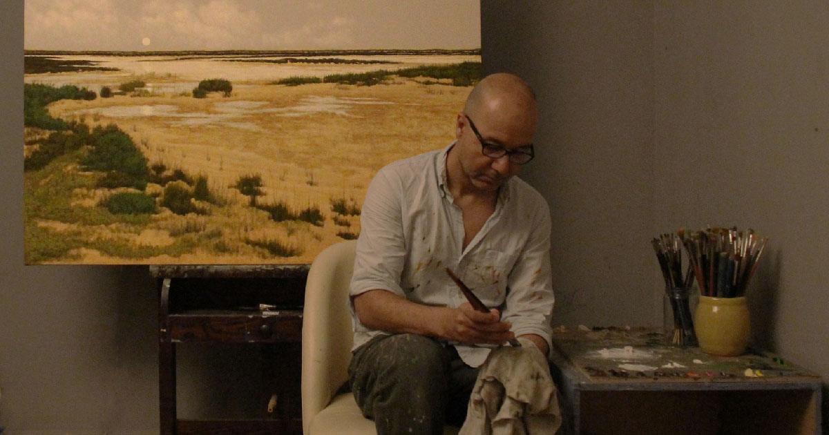 الفنان التشكيلي علي حسن مع إحد أعماله